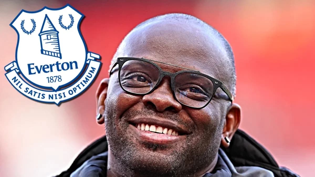 Homme souriant avec des lunettes près du logo d'Everton