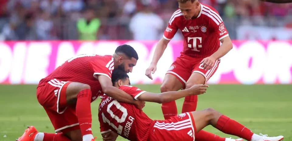 Joueurs de Bayern Munich aidant un coéquipier au sol