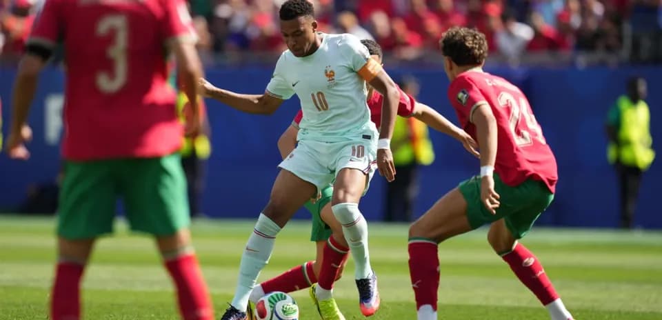 Joueur français dribblant entre deux joueurs marocains