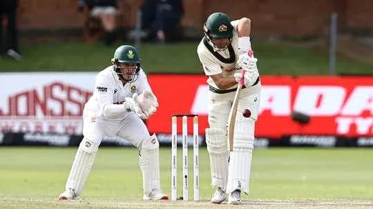 Batsman playing a shot while wicketkeeper crouches
