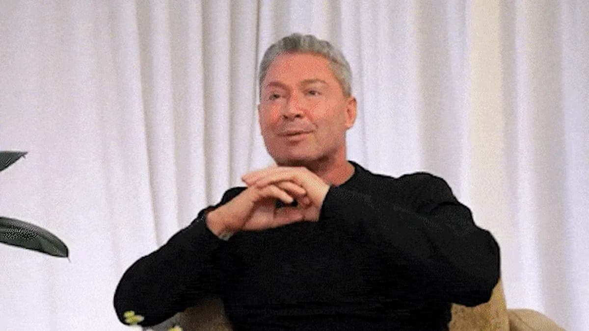 Homme parlant avec mains croisées sur genoux