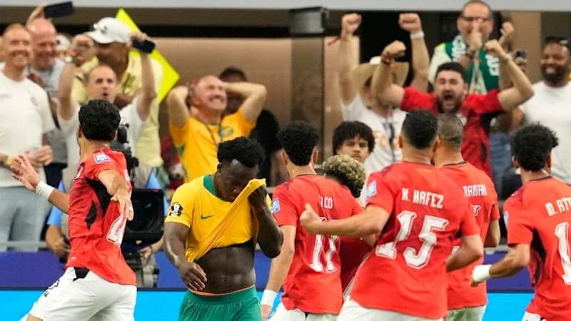 Joueurs célébrant un but avec des supporters en arrière-plan