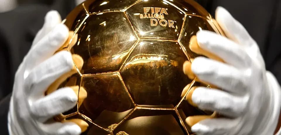 Trophée Ballon d'Or tenu par des mains gantees