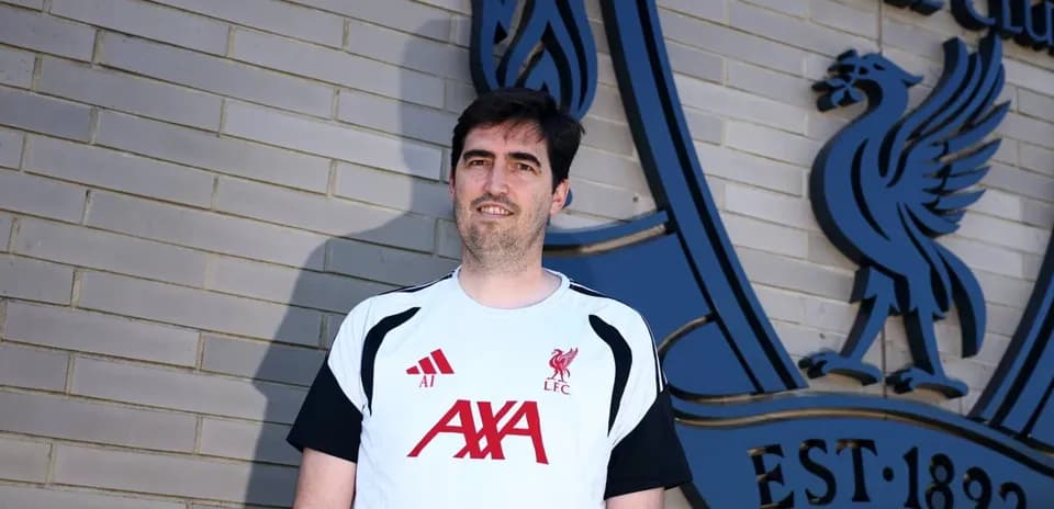 Person en tenue de Liverpool devant le logo du club