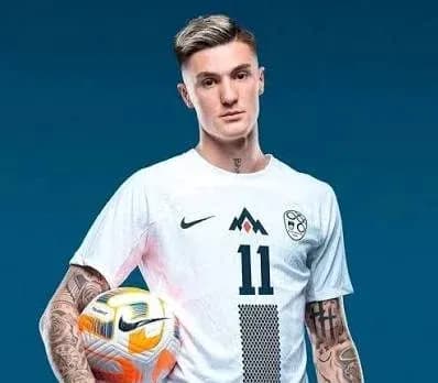 Joueur en maillot blanc tenant un ballon de football