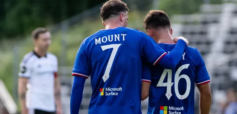 Deux joueurs en maillots bleus se parlent sur le terrain