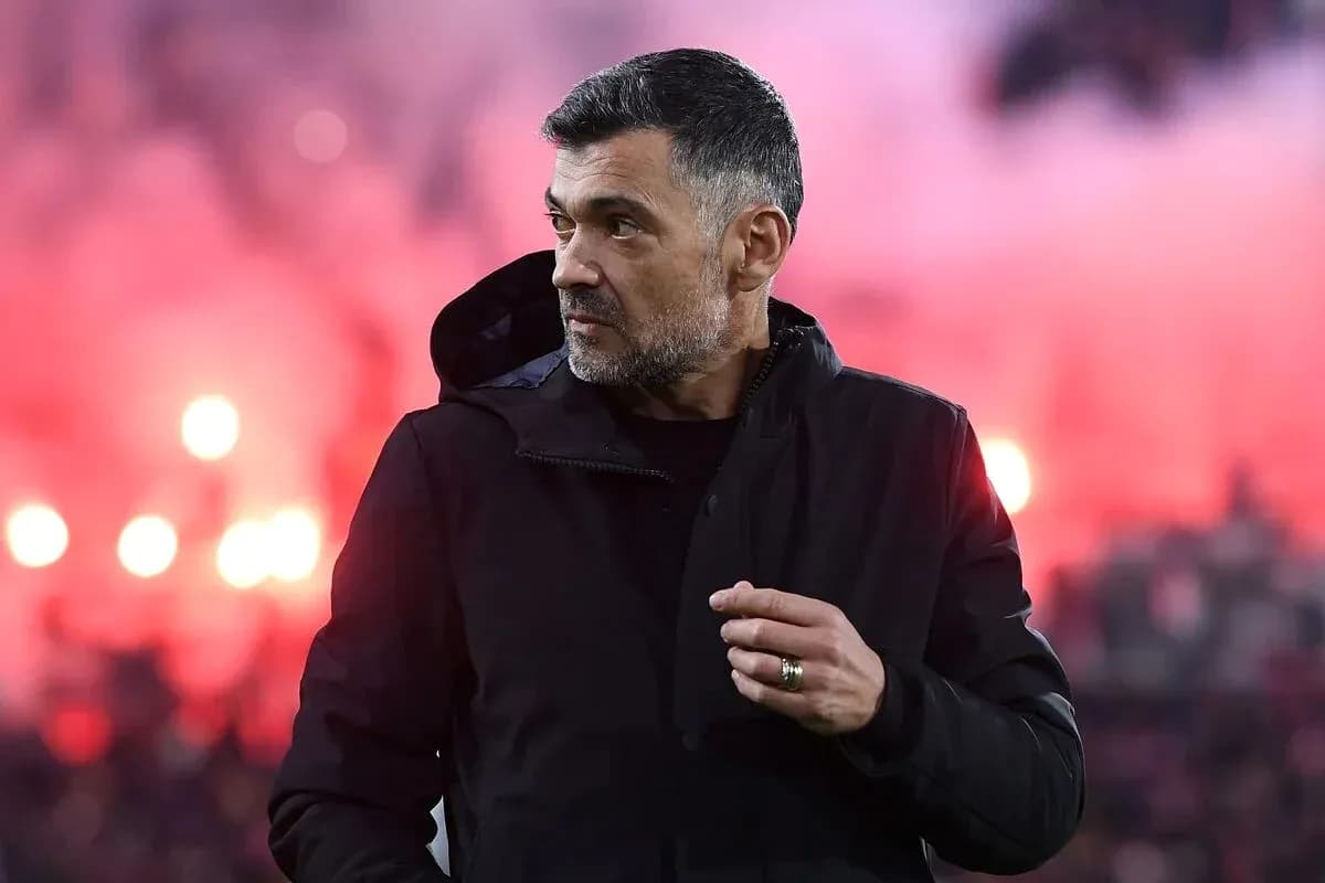Entraîneur observant le match avec des fumigènes en arrière-plan