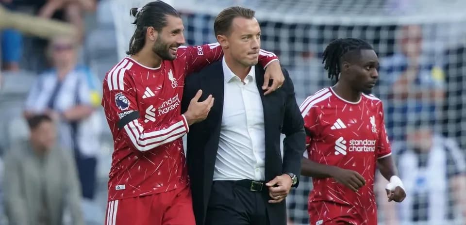 Joueurs de Liverpool entourant un entraîneur sur le terrain