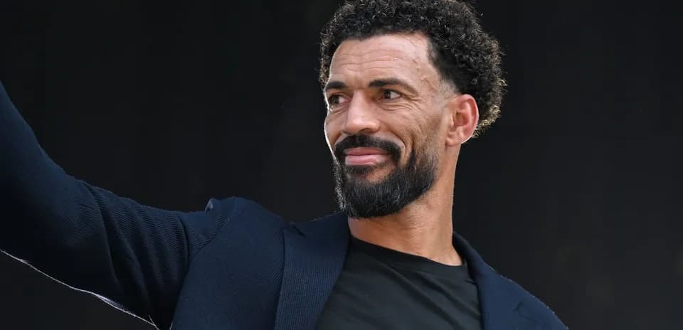 Homme souriant et levant la main sur scène