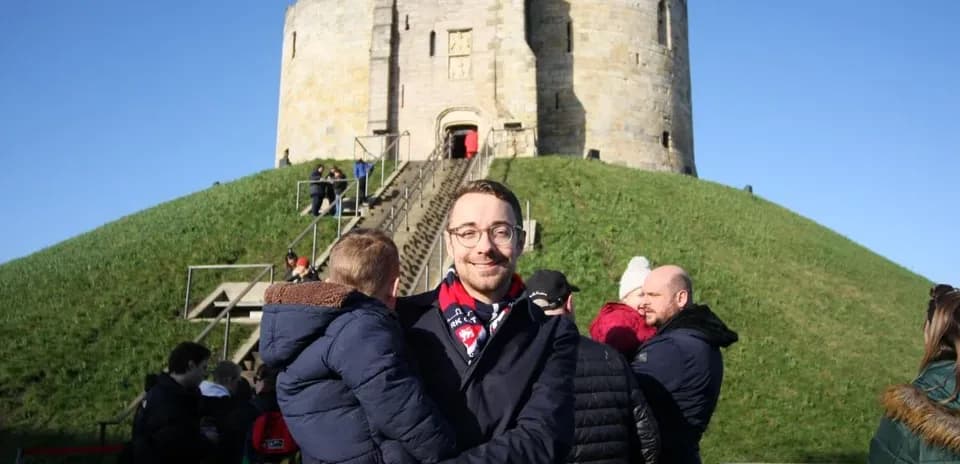 Homme tenant un enfant devant une forteresse