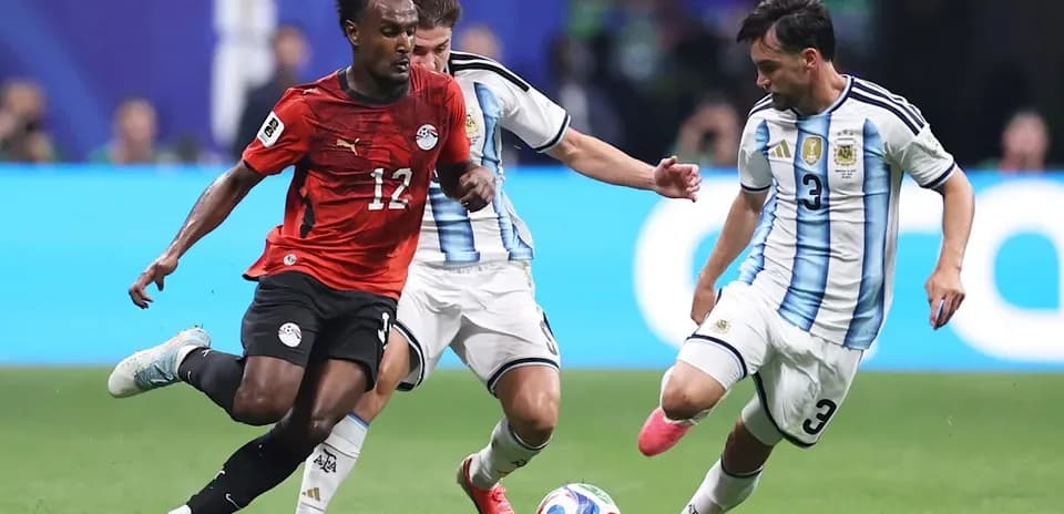 Joueur égyptien dribblant entre deux joueurs argentins