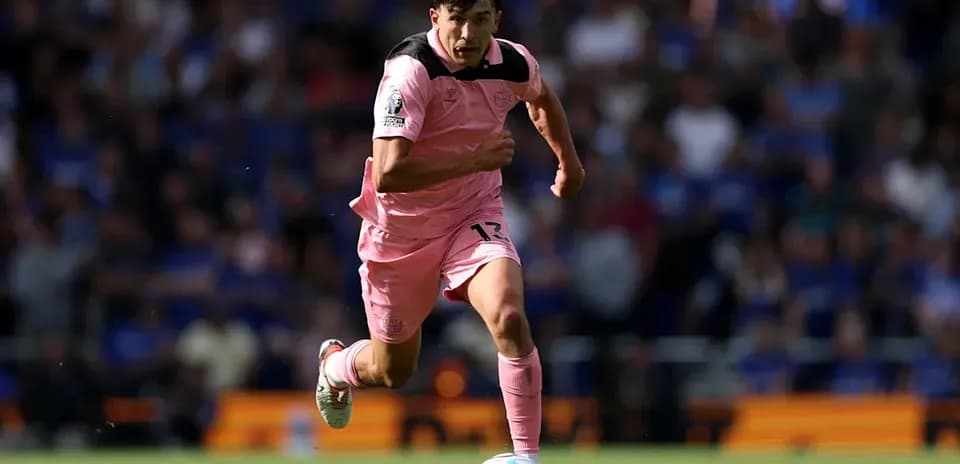 Joueur en maillot rose courant avec le ballon