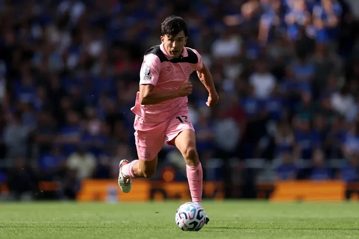 Joueur en maillot rose courant avec le ballon