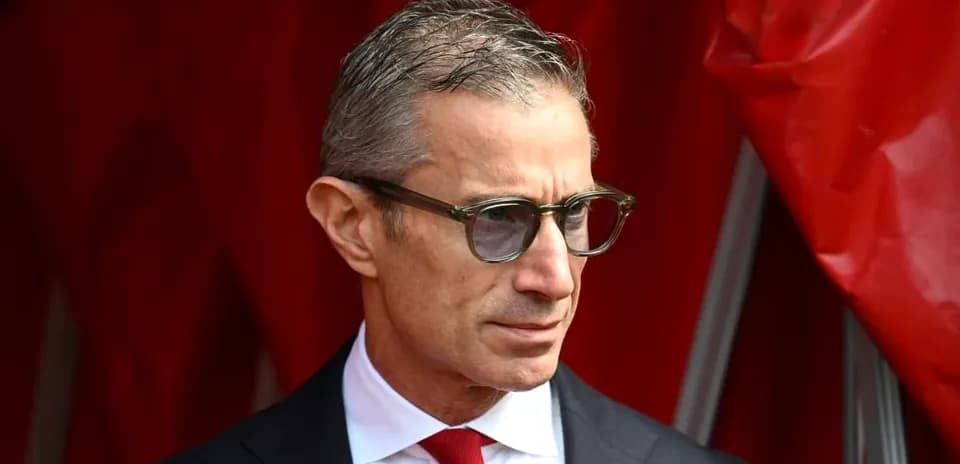 Homme en costume avec lunettes près d'un rideau rouge