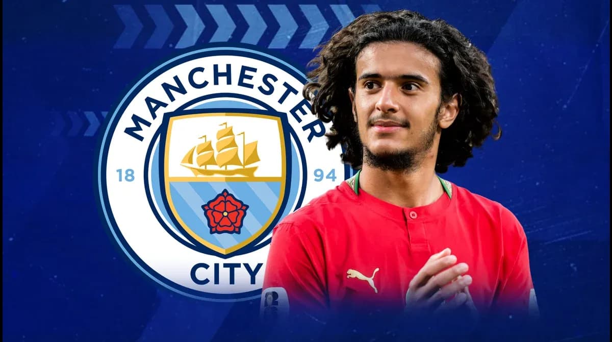 Joueur avec maillot rouge devant le logo de Manchester City