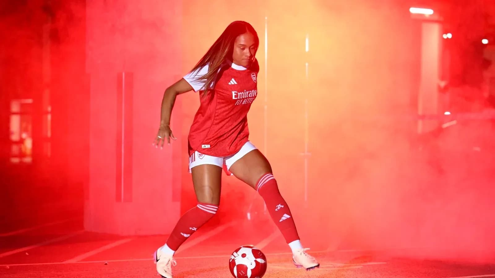 Joueuse d'Arsenal dribblant un ballon dans la fumée