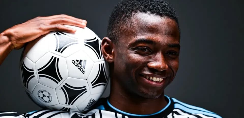 Joueur tenant un ballon de football sur l'épaule