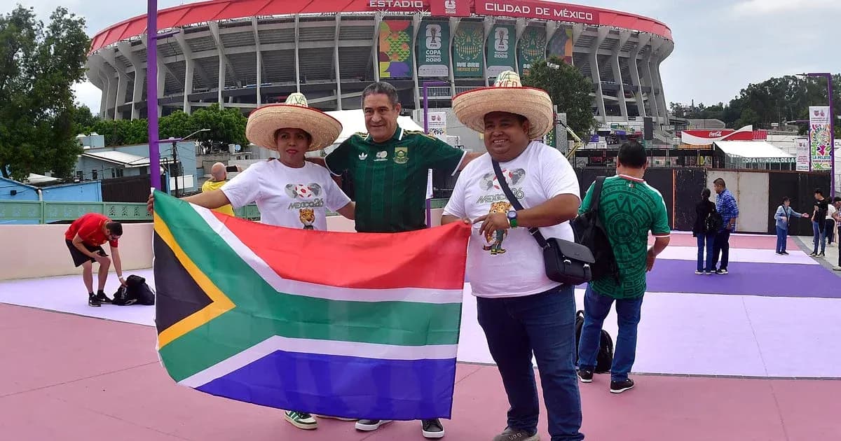 Trois supporters avec un drapeau sud-africain devant le stade