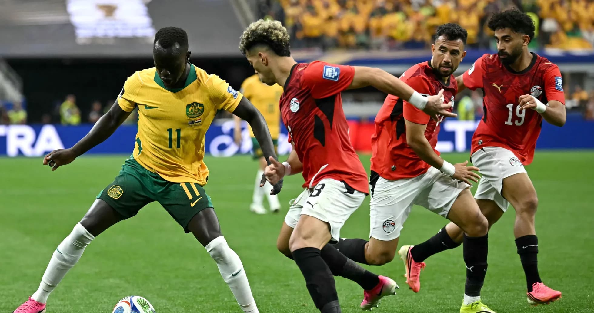 Joueur australien dribblant face à des joueurs égyptiens