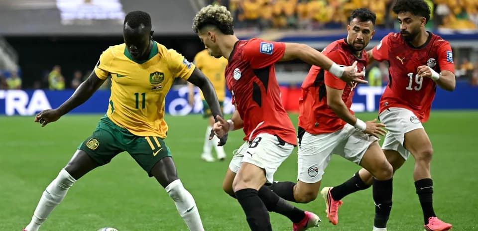 Joueur australien dribblant face à des joueurs égyptiens