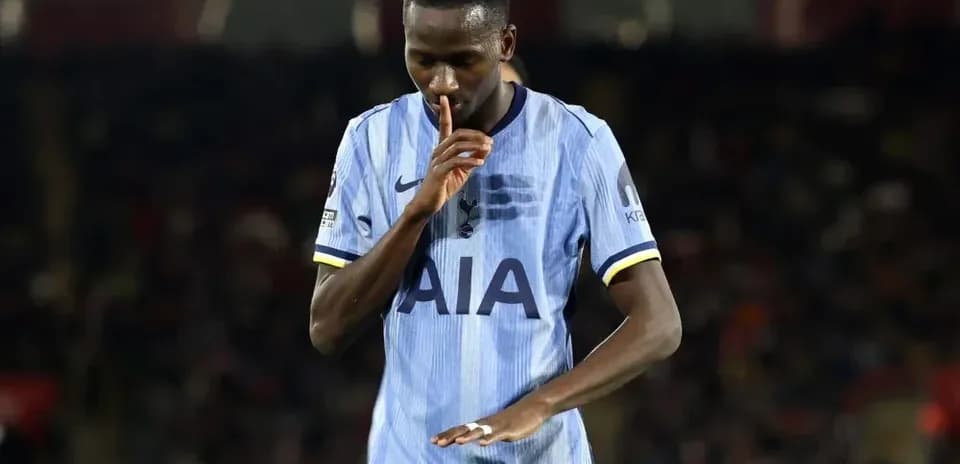 Joueur en maillot de Tottenham faisant un geste de silence