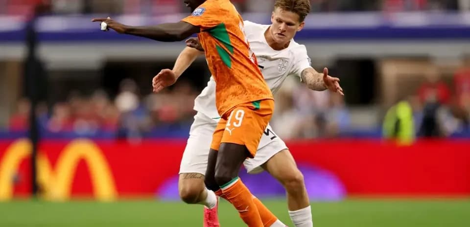 Joueur en orange dribblant sous la pression d'un adversaire
