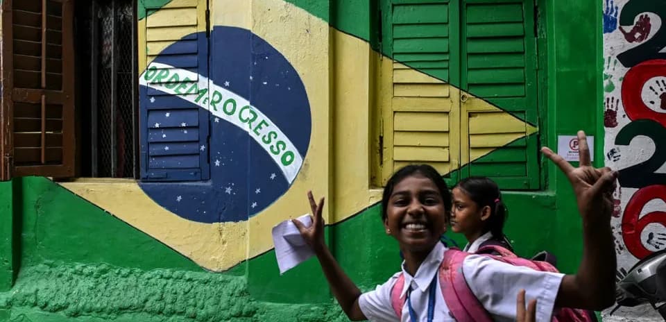 Enfant souriante devant un mur avec drapeau brésilien