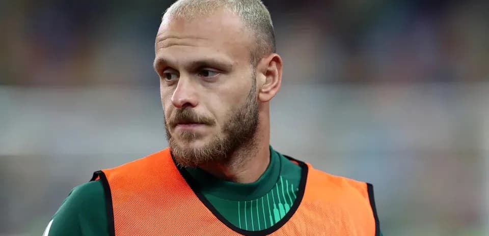 Joueur en survêtement avec un gilet orange sur le banc