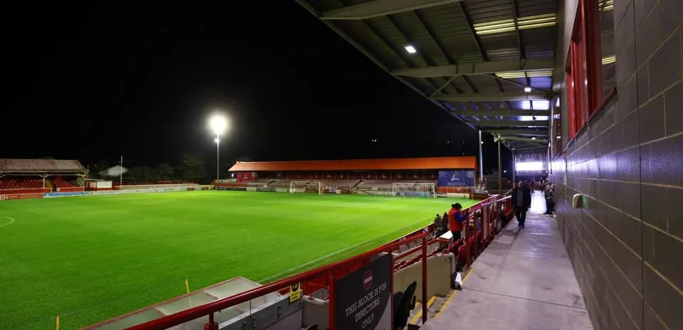 Stade de football éclairé la nuit avec gradins vides