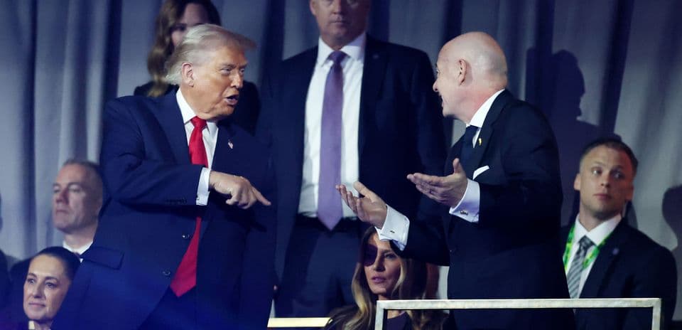 Deux hommes discutant lors d'un événement, spectateurs en arrière-plan