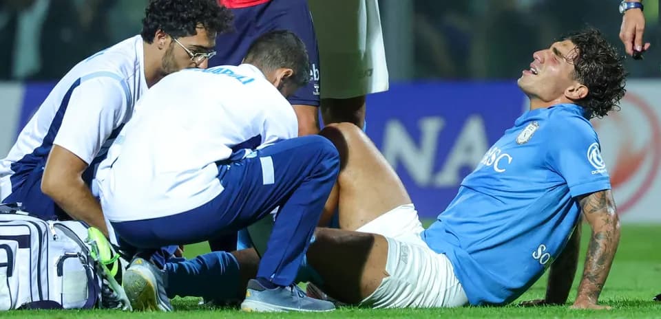 Joueur blessé avec deux entraîneurs sur le terrain