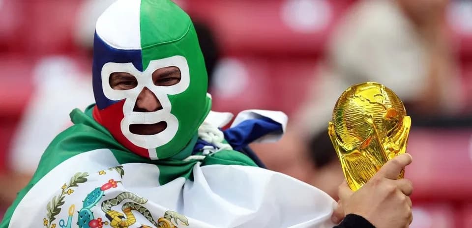 Supporter wearing mask holding FIFA World Cup trophy