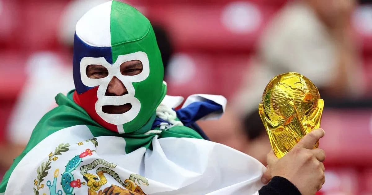 Supporter wearing mask holding FIFA World Cup trophy