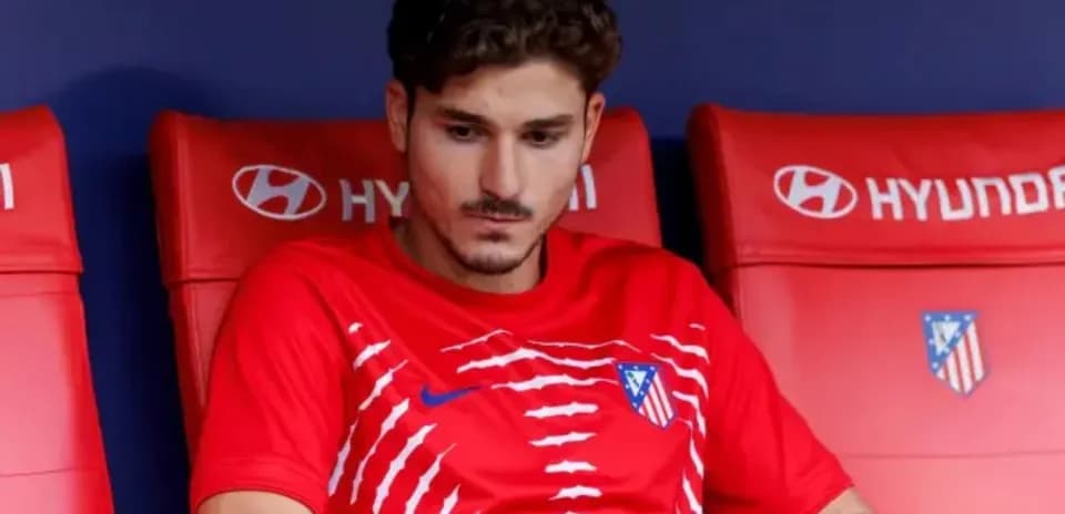 Joueur assis sur le banc de touche avec maillot rouge