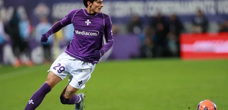 Joueur en maillot violet courant vers le ballon