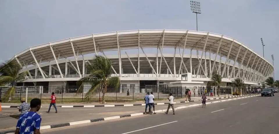 Vue extérieure d'un stade avec passants et voitures