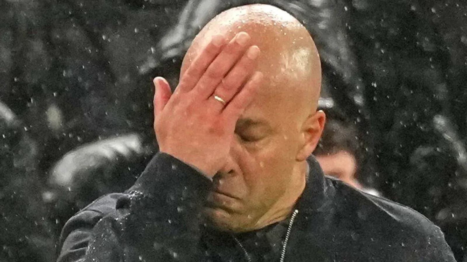Entraîneur se tenant le front sous la pluie