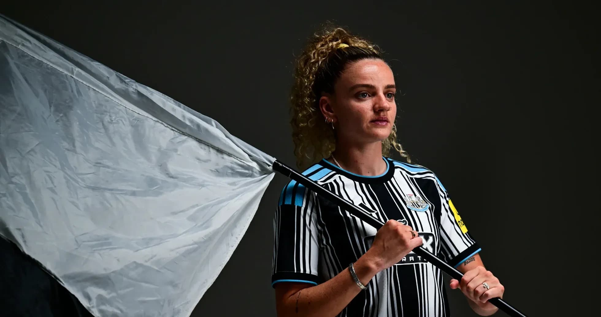 Joueuse tenant un drapeau, portant un maillot de Newcastle