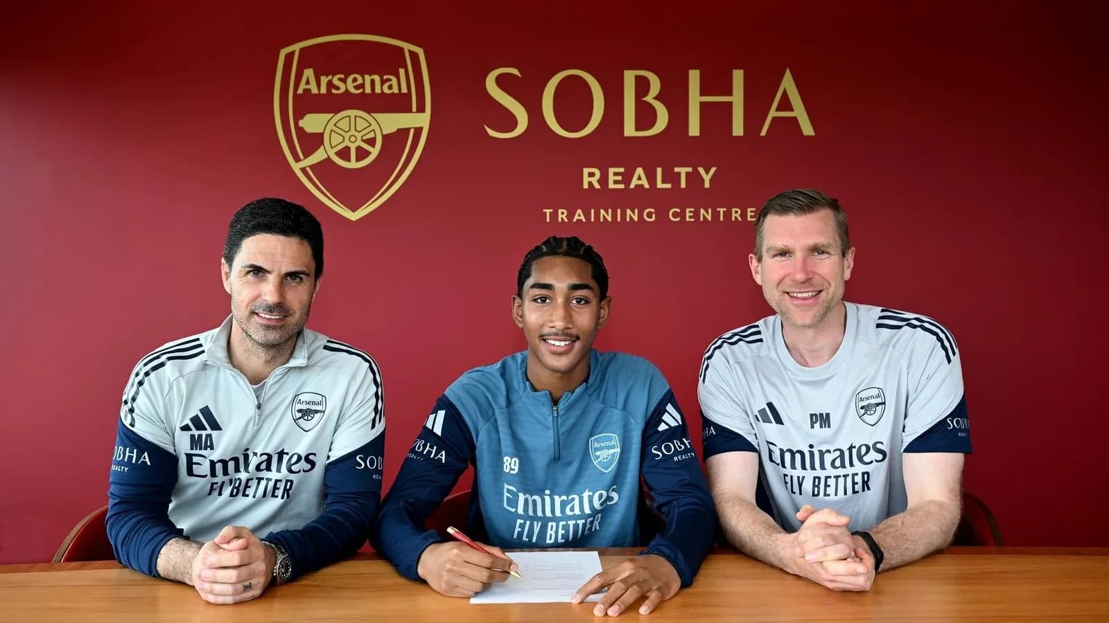 Joueur signant contrat avec entraîneurs à Arsenal