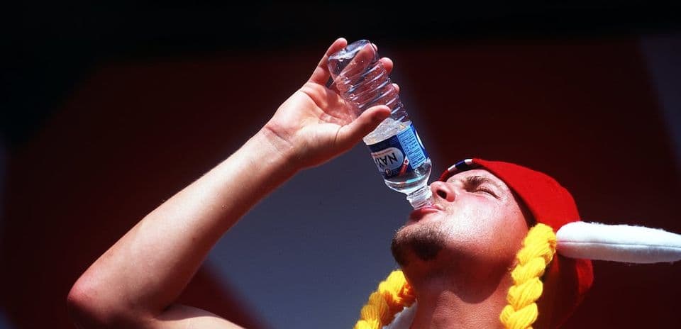 Homme buvant de l'eau en portant un chapeau