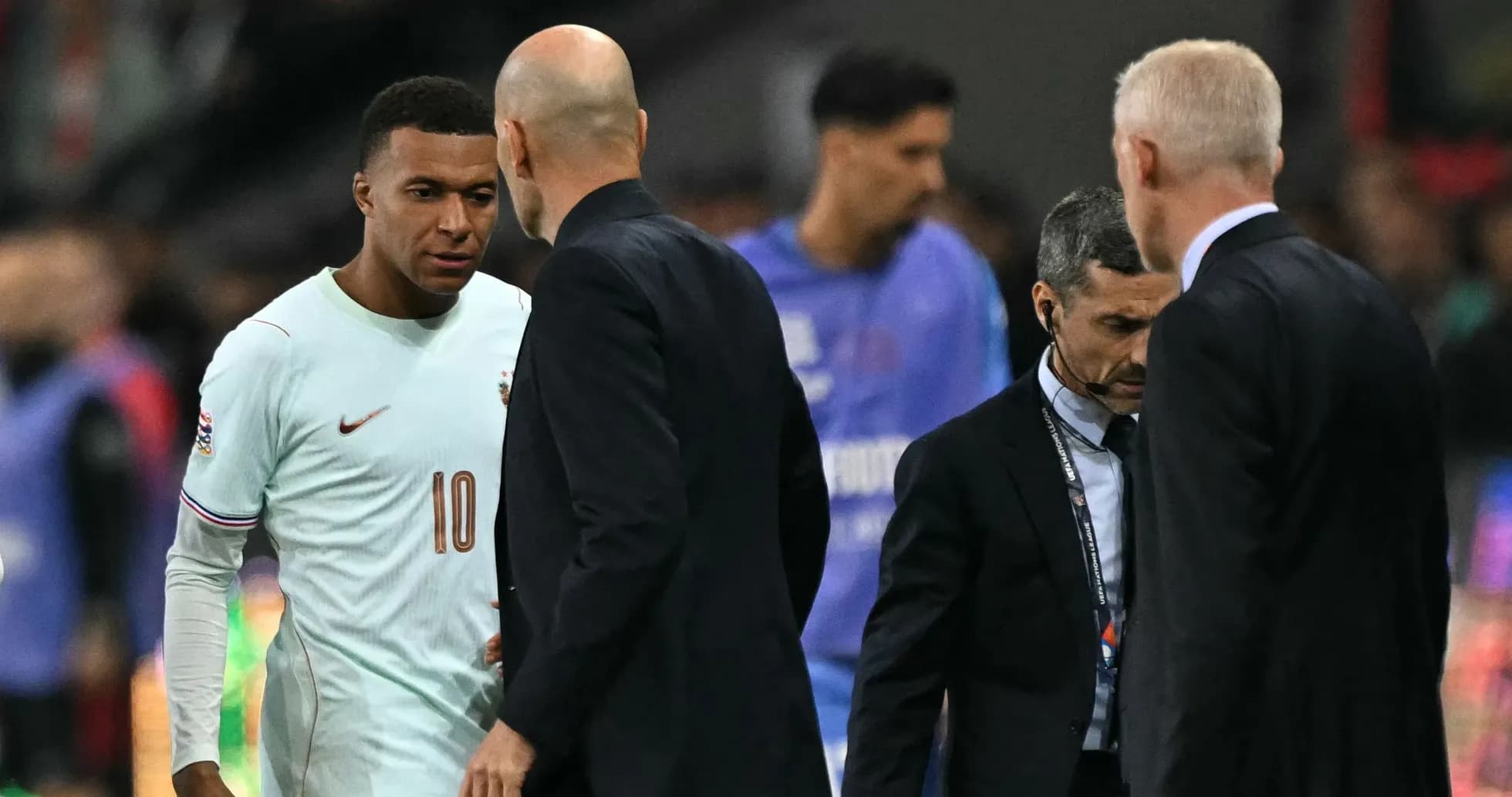 Kylian Mbappé conversing with coaches on field