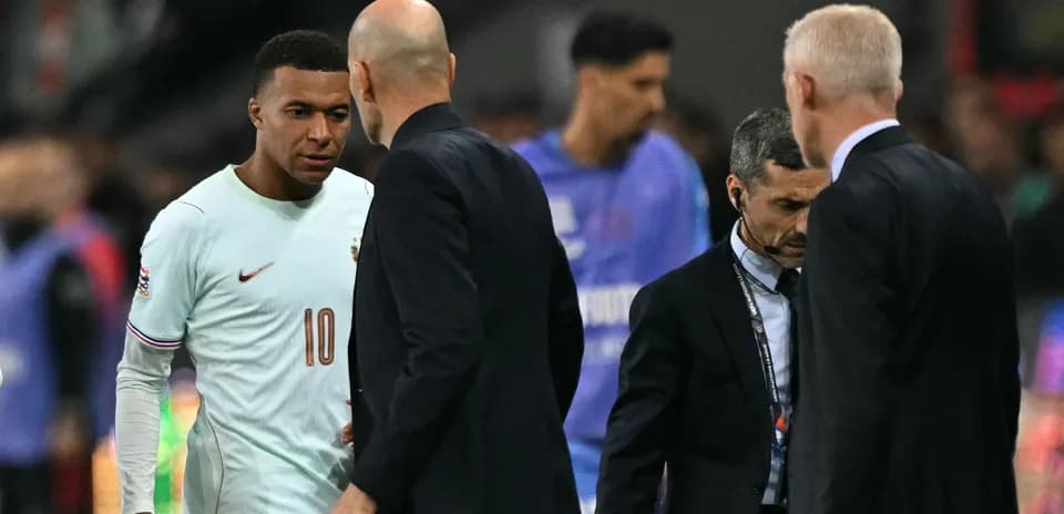 Kylian Mbappé conversing with coaches on field