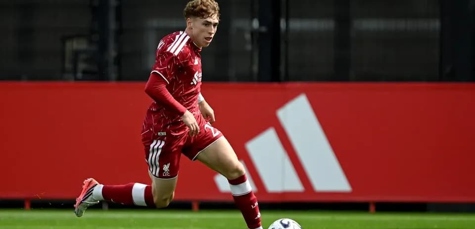 Joueur en maillot rouge dribblant avec le ballon