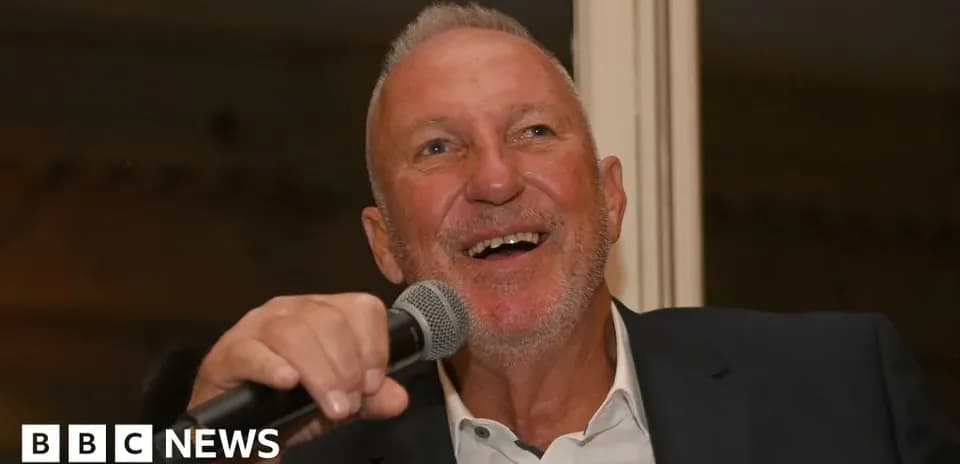 Homme souriant tenant un micro lors d'un événement