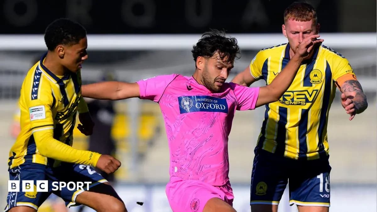 Joueur en rose dribblant entre deux adversaires en bleu