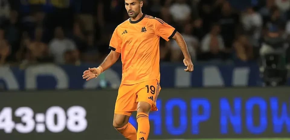 Joueur en maillot orange dribblant le ballon sur le terrain