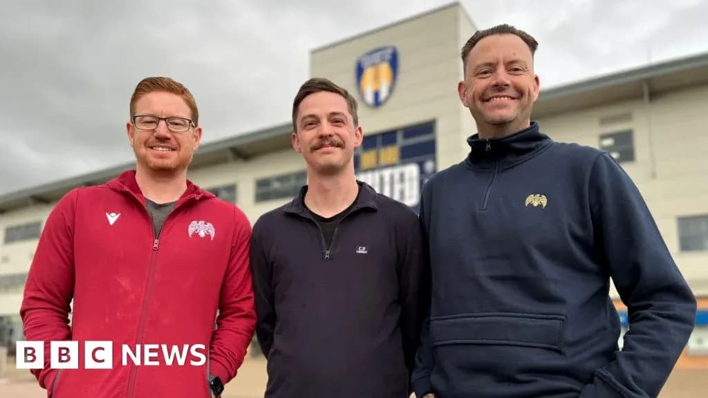 Trois hommes posant devant un bâtiment sportif