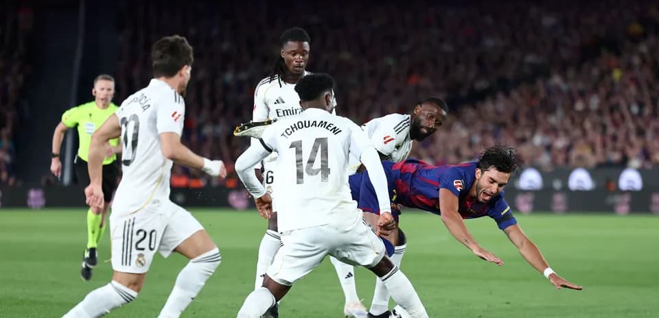 Joueur de Barcelone tombant sous la pression des défenseurs madrilènes