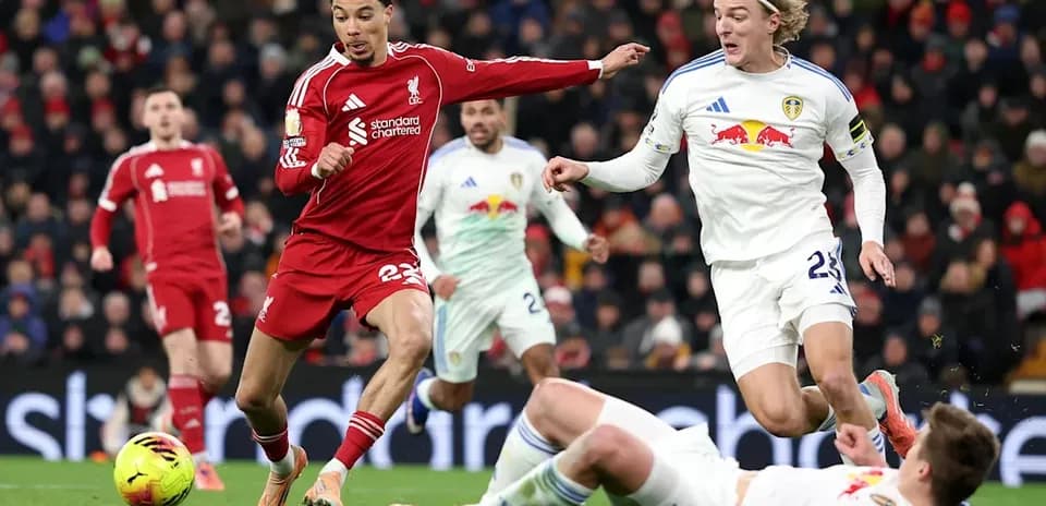 Joueur de Liverpool dribblant entre deux joueurs de Leeds