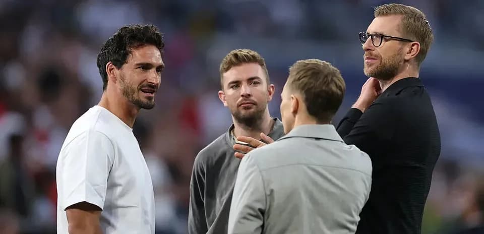Quatre hommes discutant sur le terrain de football